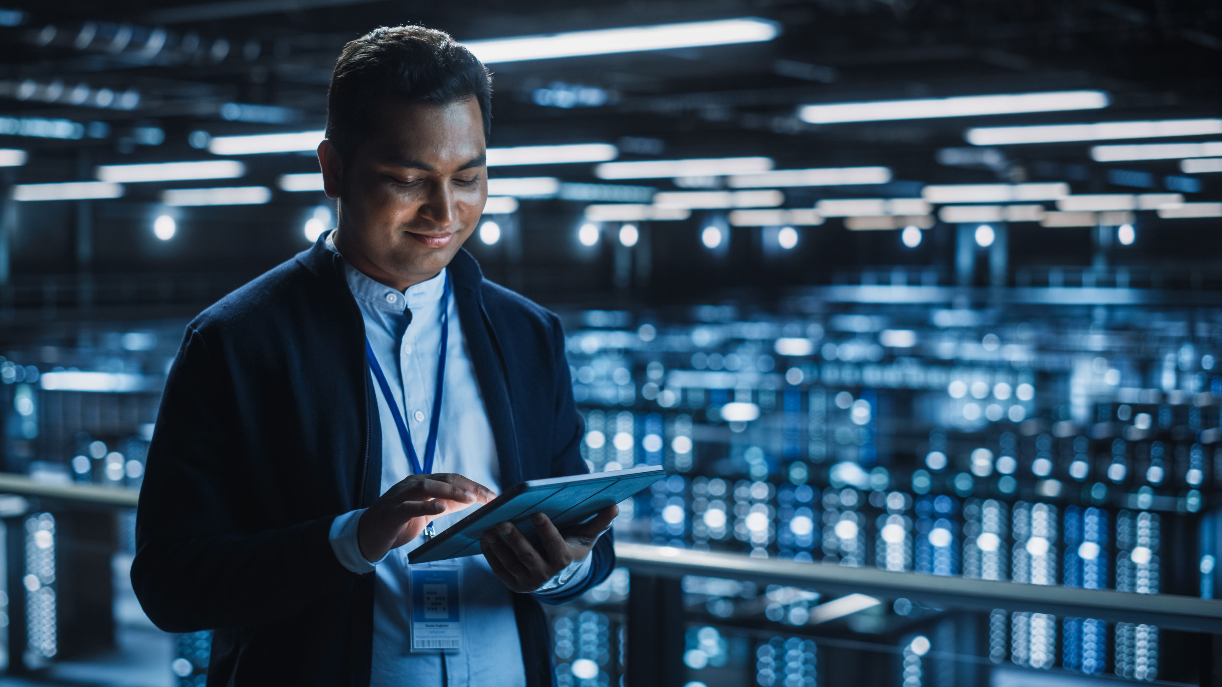 IT engineer smiling while working on a tablet in a data center