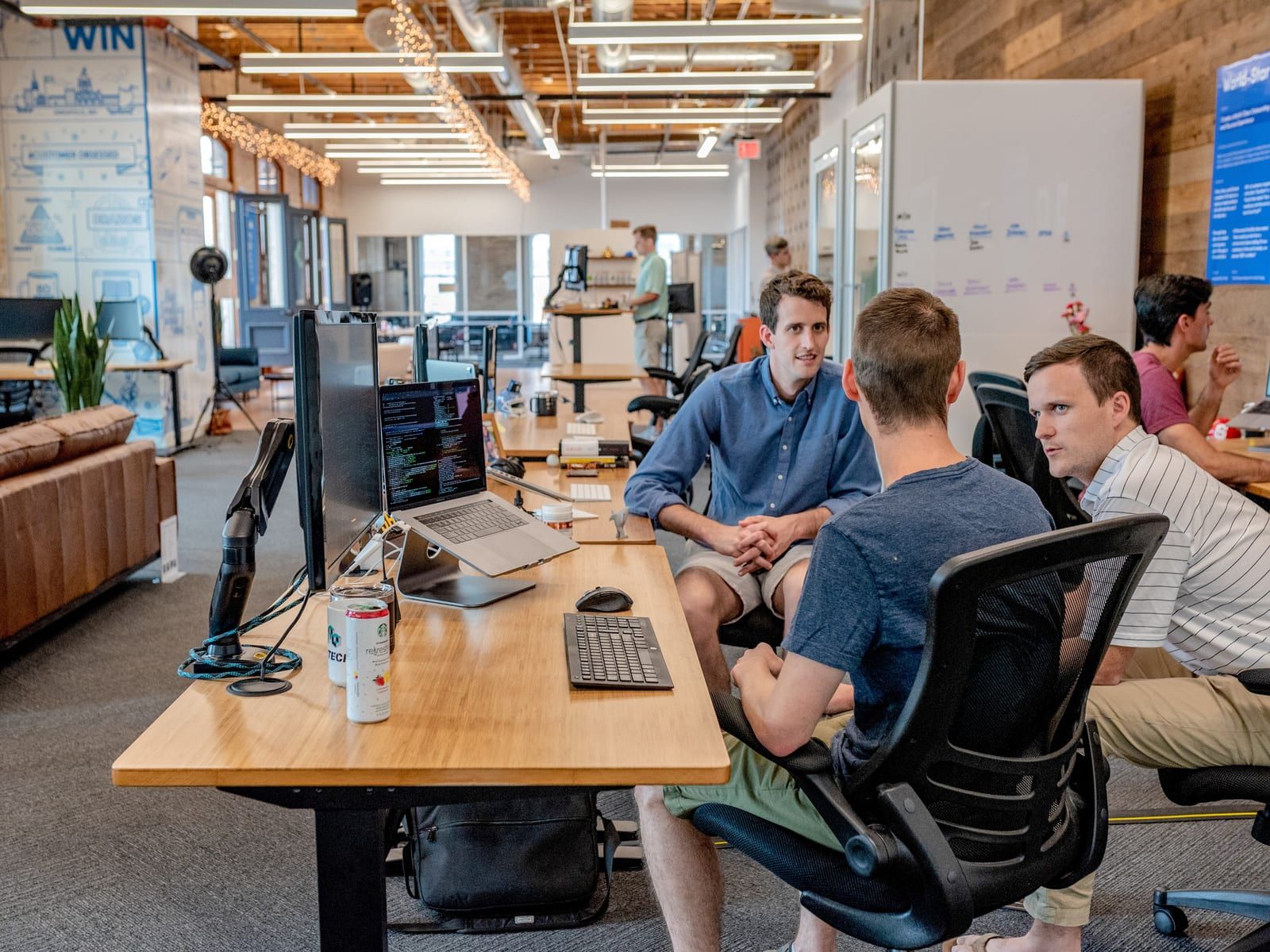 Colleagues discussing work at desks in an open-plan office