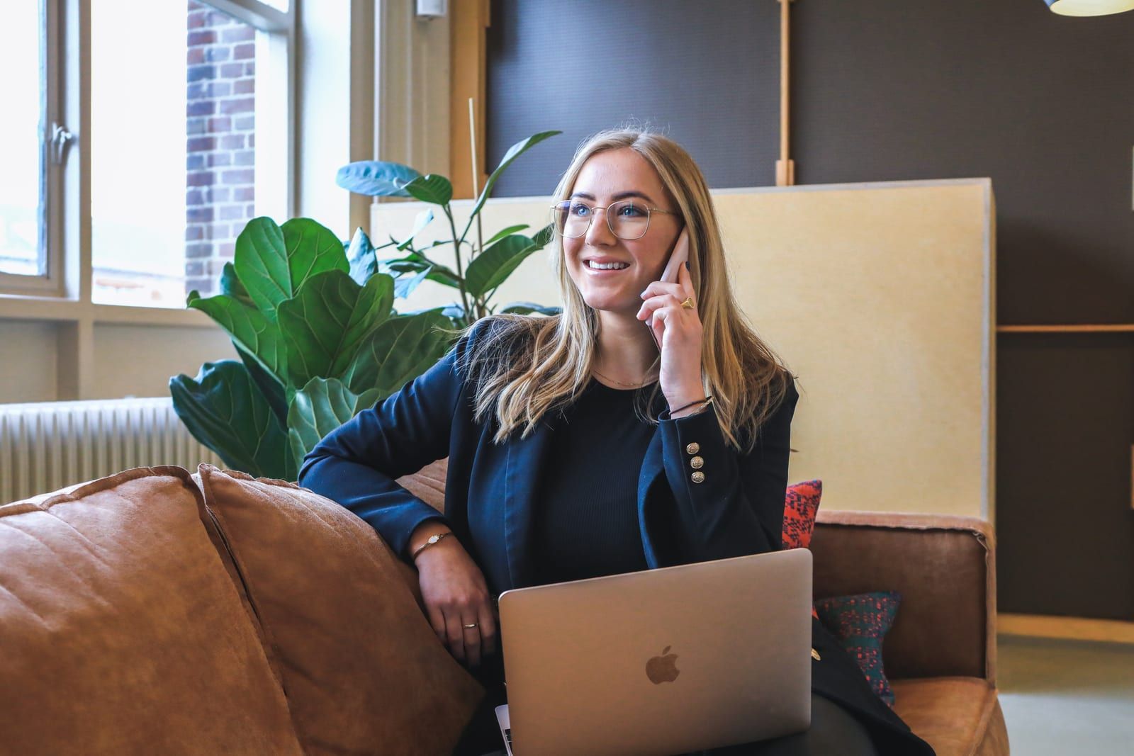 Professional on a phone call with a laptop on a sofa